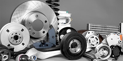 Assorted car parts including brake discs, suspension springs, and a radiator against a gray background.